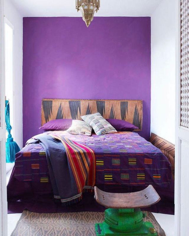 Яркая спальня в пурпурных тонах: фиолетовая акцентная стена, цветные текстили и деревянное изголовье создают насыщенный, но компактный интерьер.