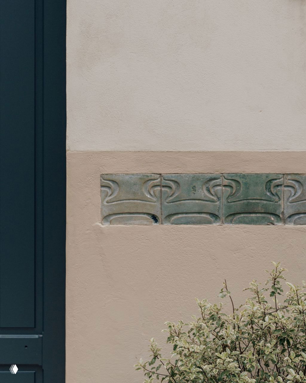 Деталь фасада: ряд зелёных мозаичных вставок на стене — обнаруженные элементы ар-нуво, которые стали отправной точкой для отделки интерьера.