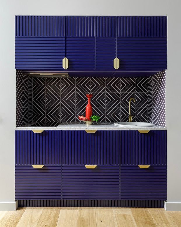 Глубокие синие фасады кухни с рифлёной фактурой и контрастной чёрно‑белой фартукой в графический узор, минимальная рабочая поверхность.