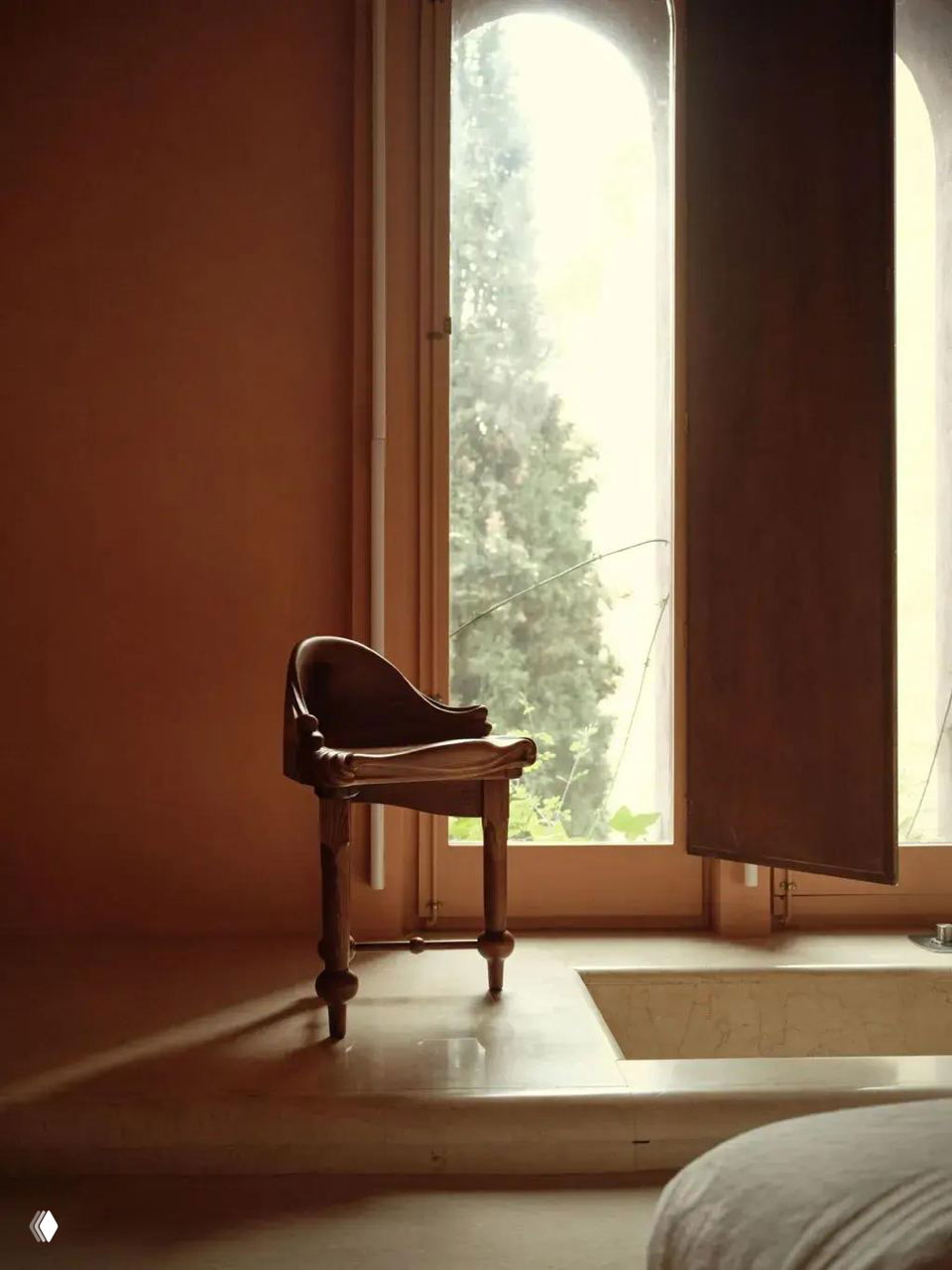 Одиночный деревянный стул у большого окна: плавные органические линии, тёплый дубовый тон и вид на внешнюю зелень через высокое окно.
