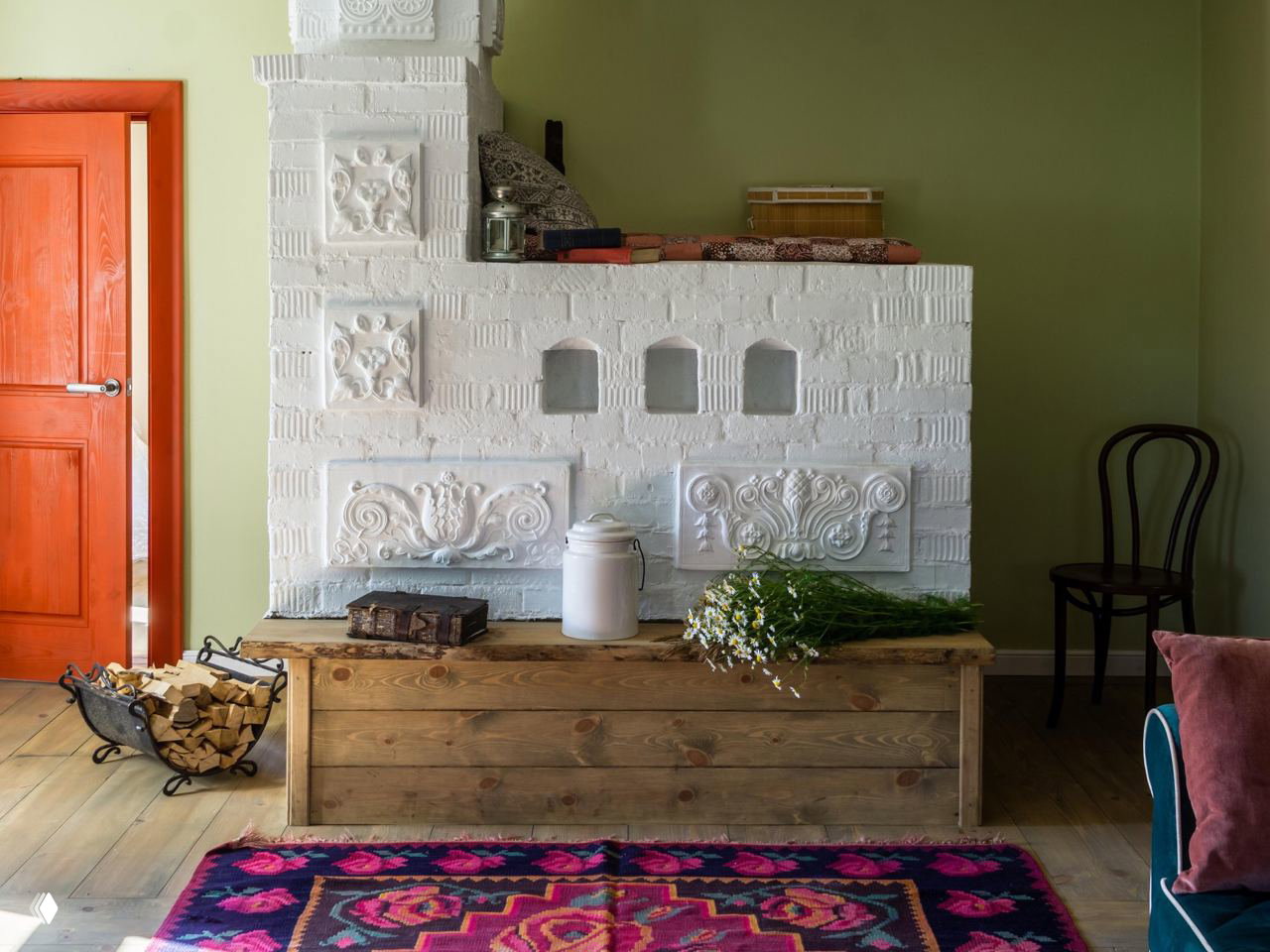 Интерьер традиционной русской печи и деревянной скамьи с цветочным ковром, элементы декора в уютной деревенской комнате в суздальском стиле.