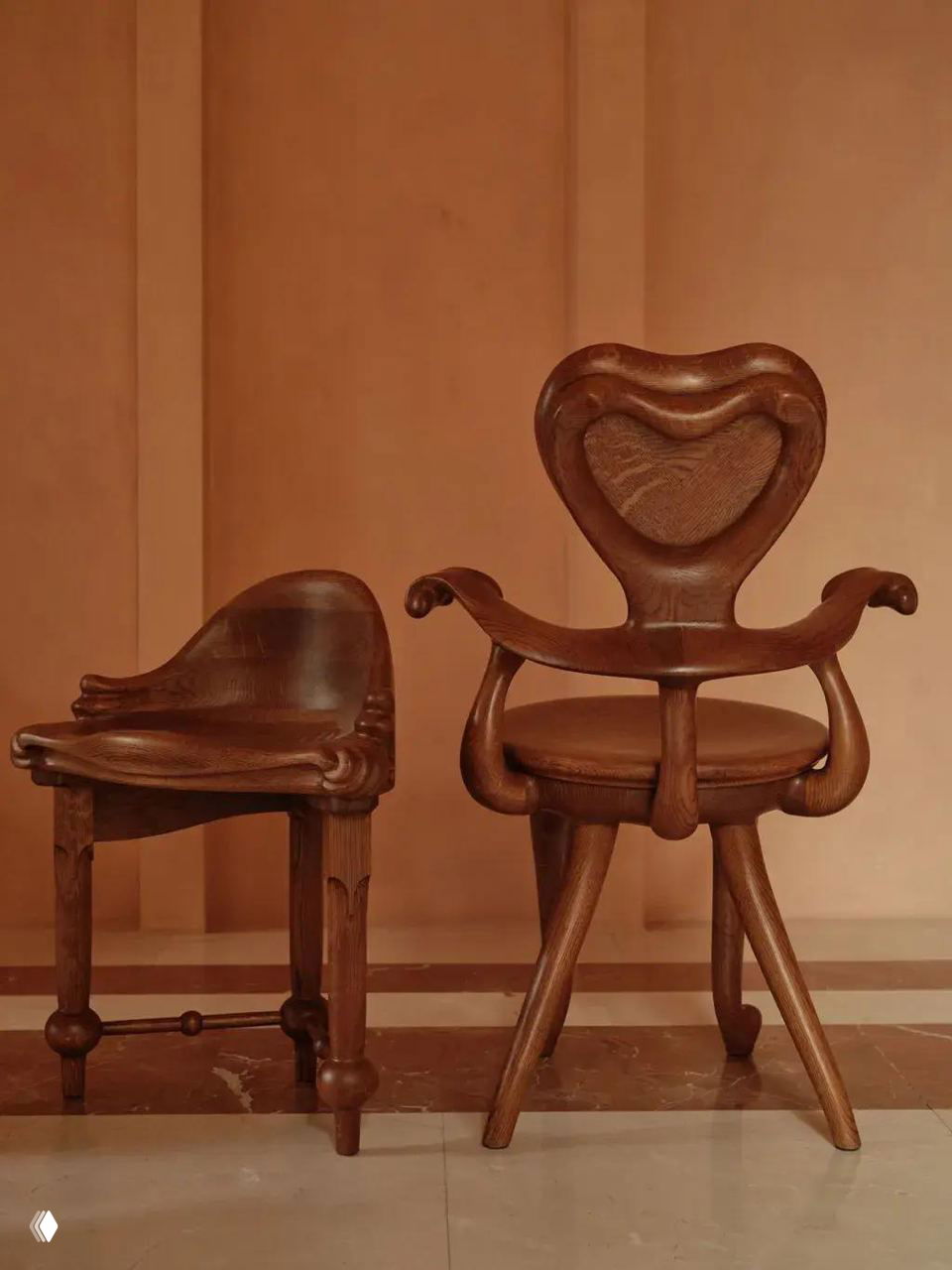 Два кресла из дуба вблизи: рельефные спинки в форме сердца, закруглённые подлокотники и полированная текстура дерева — детали в духе Гауди.