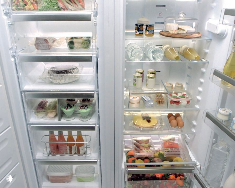 Открытый двухдверный холодильник с упорядоченными полками, бутылками, контейнерами и отделениями для сыра, яиц и овощей.