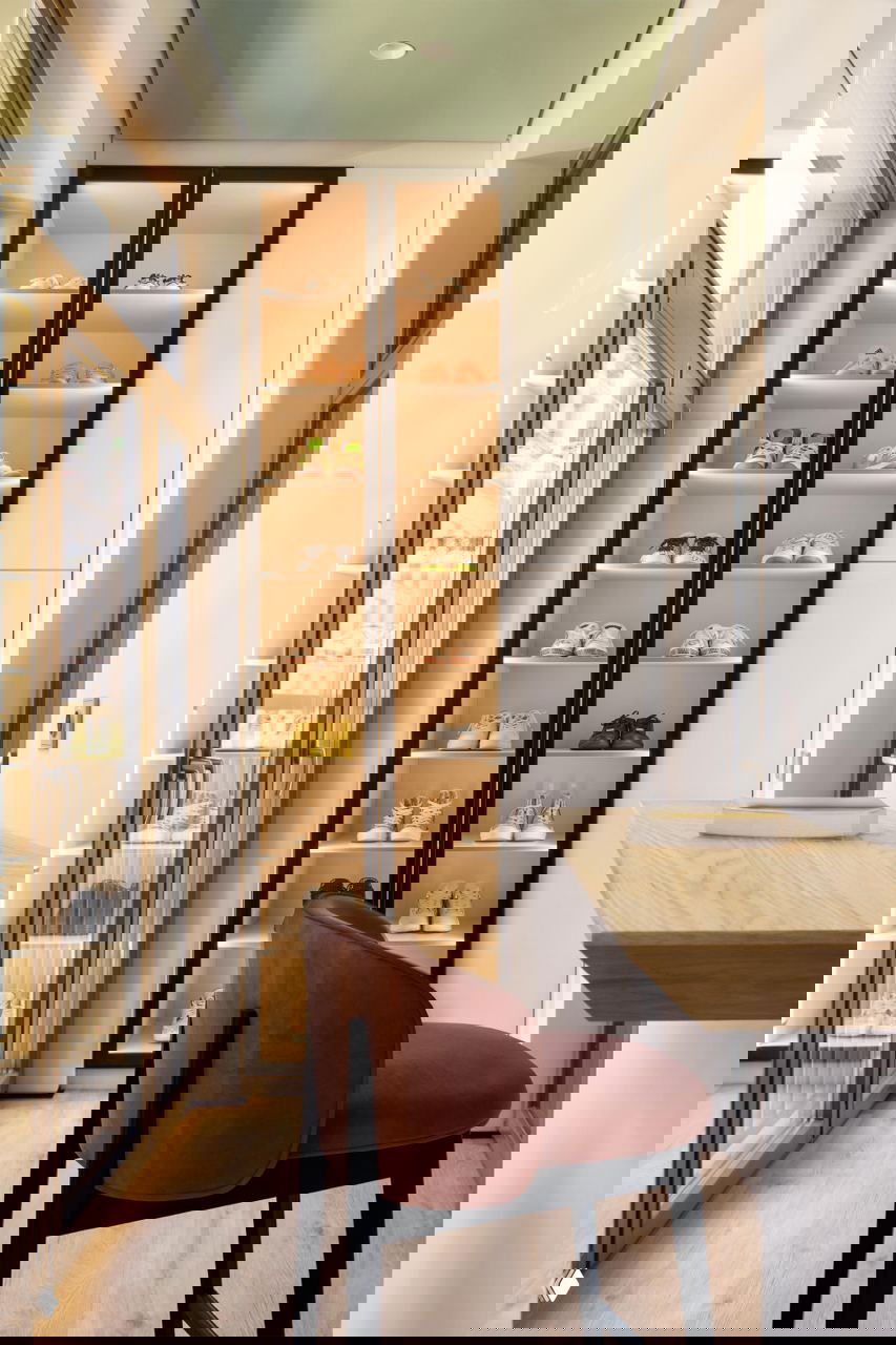 Узкая рабочая зона с подсвеченным стеллажом для обуви, барной стойкой у окна и светлой деревянной отделкой — компактное функциональное решение в коридоре.