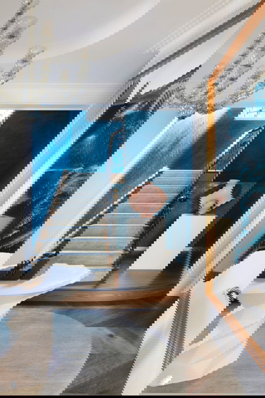 Прихожая и лестница: бетонные ступени, чёрная кованая перила, насыщенные синие стены, постамент со скульптурой.