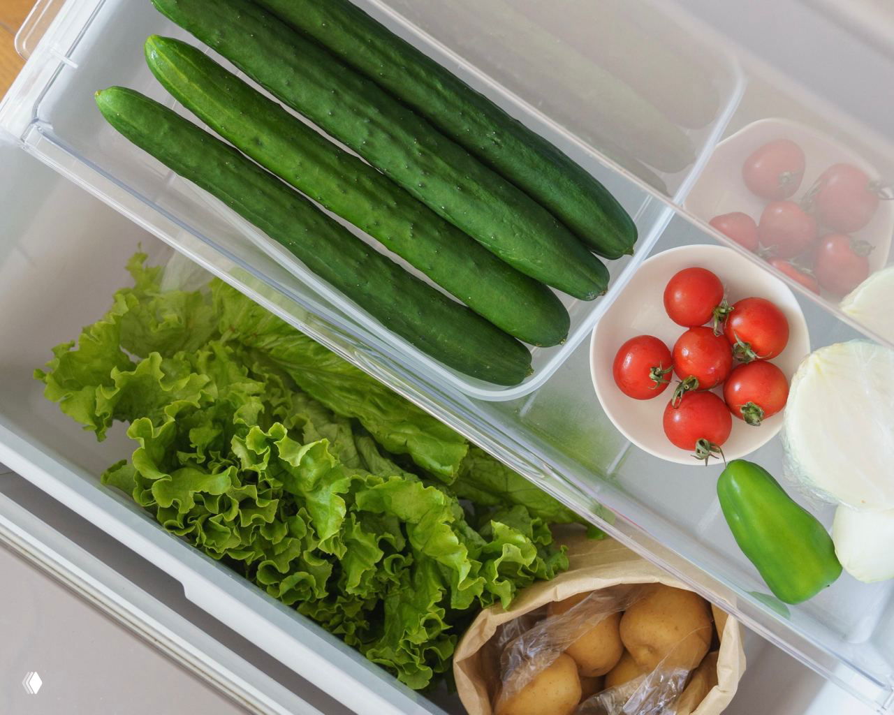 Выдвижной ящик холодильника с огурцами, помидорами и зеленью в отдельных отделениях — аккуратное хранение скоропортящихся овощей.