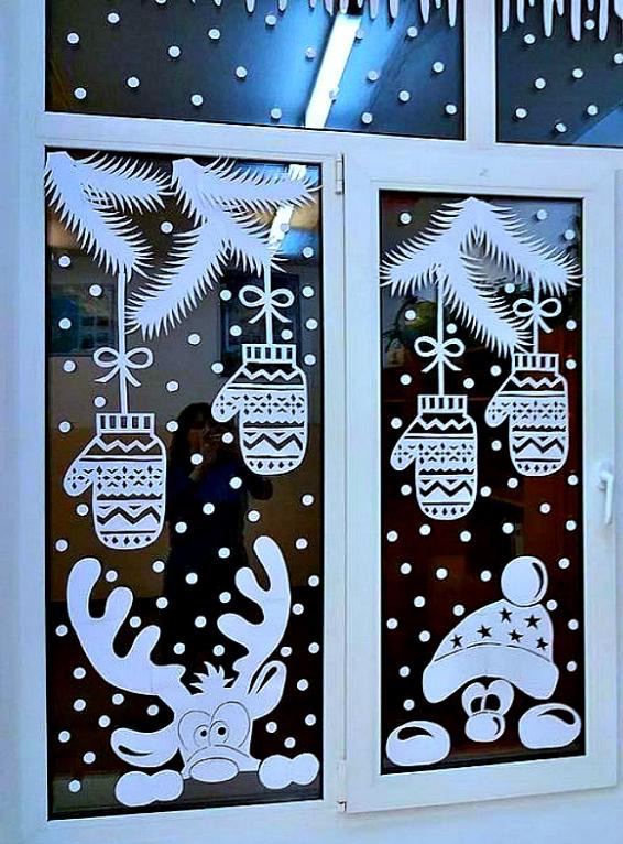 Новогодняя вытынанка на окне: подвесные игрушки, олень и медвежонок, снежинки и гирлянды на тёмном фоне — сезонный бумажный декор.