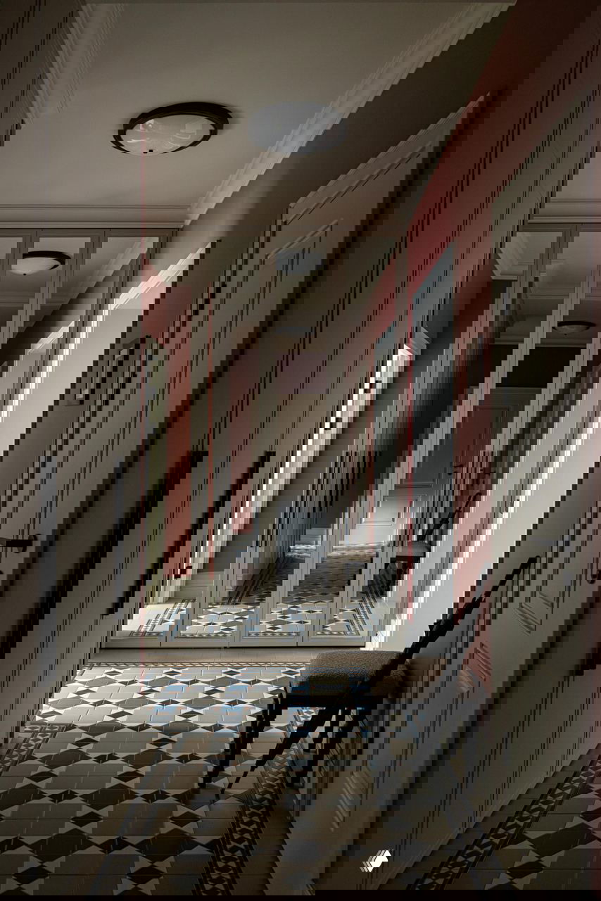 Прихожая с зеркальными дверцами шкафа, терракотовыми стенами и декоративной мозаичной плиткой на полу в классическом узоре.