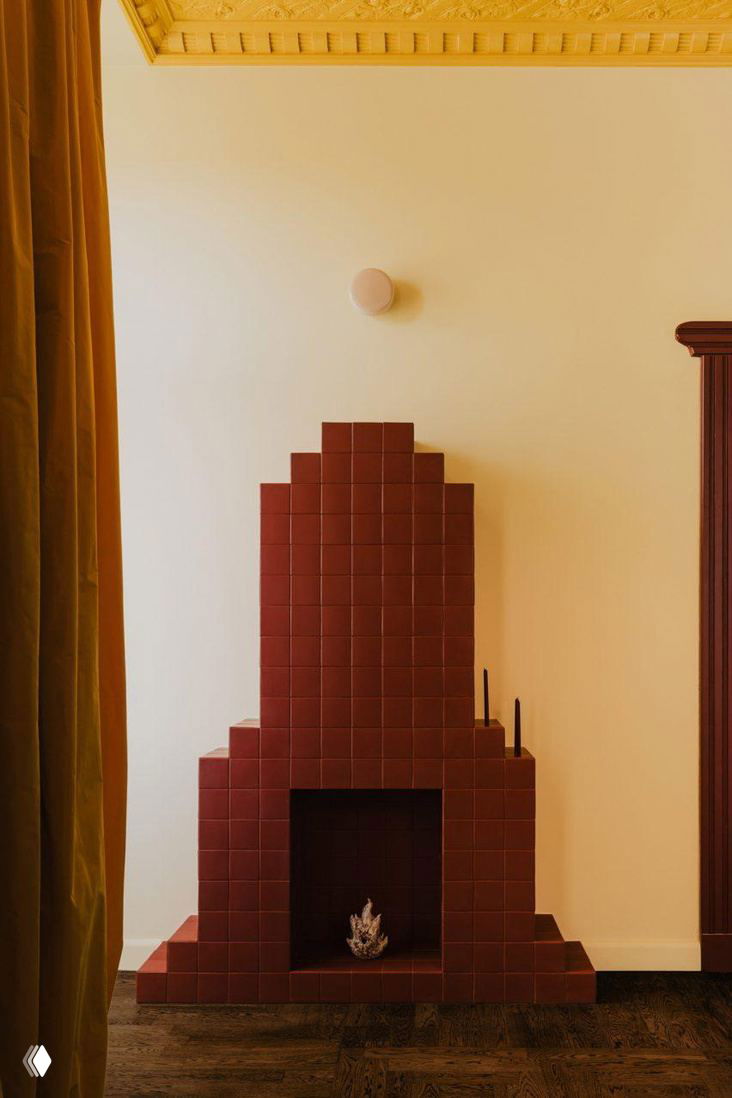 Керамический тёмно-бордовый камин в минималистичной нише — аккуратный винтажный элемент в ансамбле современной мебели и цвета.