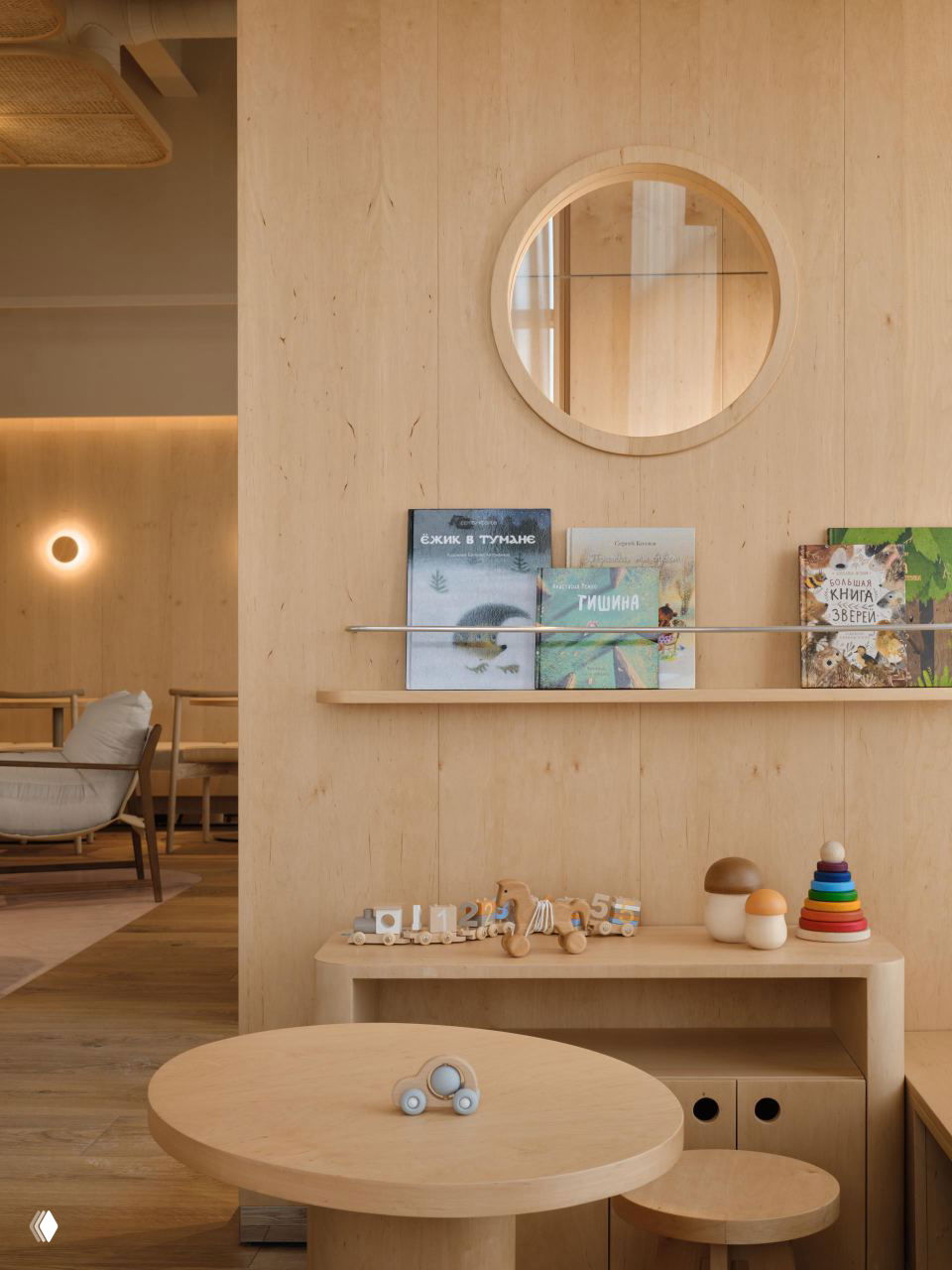 Детская/игровая зона в кафе с деревянной мебелью, круглыми столами, книжками на полке и деревянными развивающими игрушками — пространство продумано для семейных гостей.
