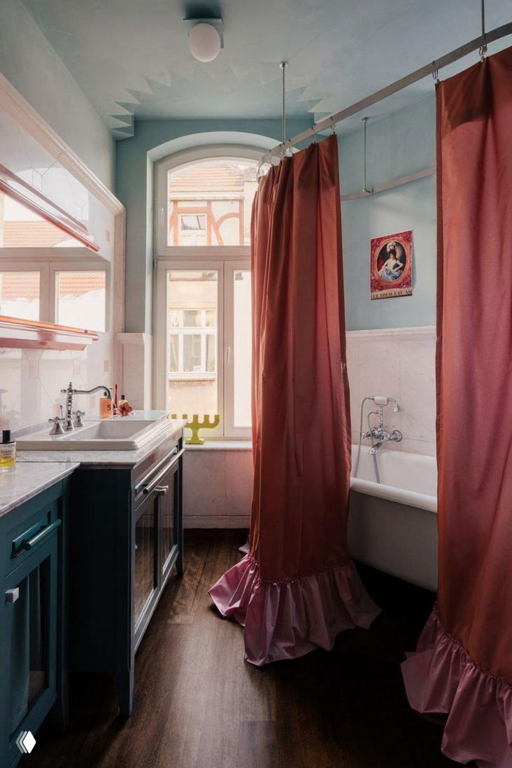 Ванная комната с бирюзовыми стенами и розовыми шторками вокруг ванны, контрастное сочетание пастельных и насыщенных тонов в небольшой планировке.