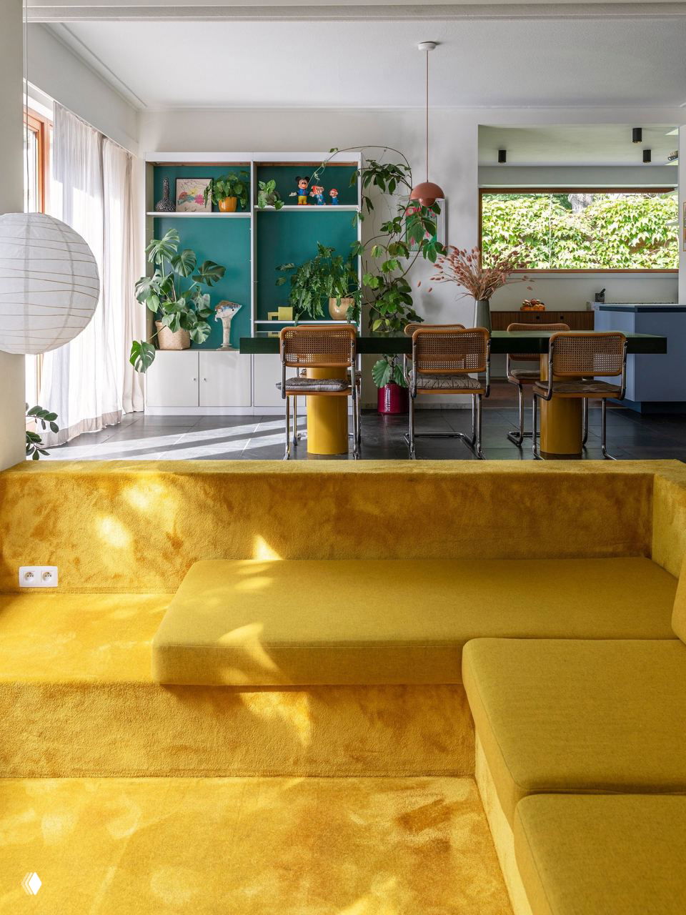 Яркая желтая утопленная в пол зона с мягким покрытием и ступенями, эффектно вписанная в открытую гостиную с видом на столовую и зелень.