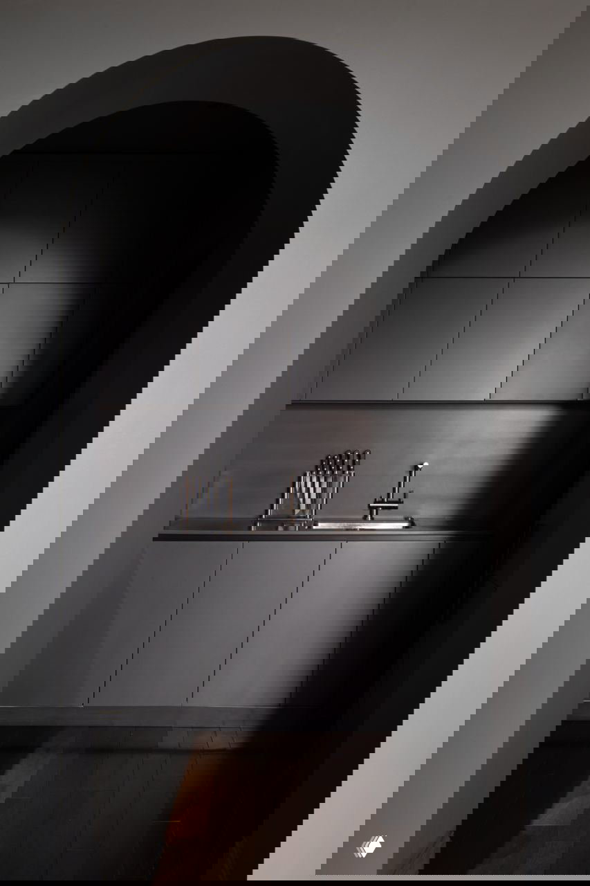 Арочный проход в кухню в тёмных матовых тонах: минималистичные шкафы, встроенная мойка и строгая архитектура арки в интерьере квартиры