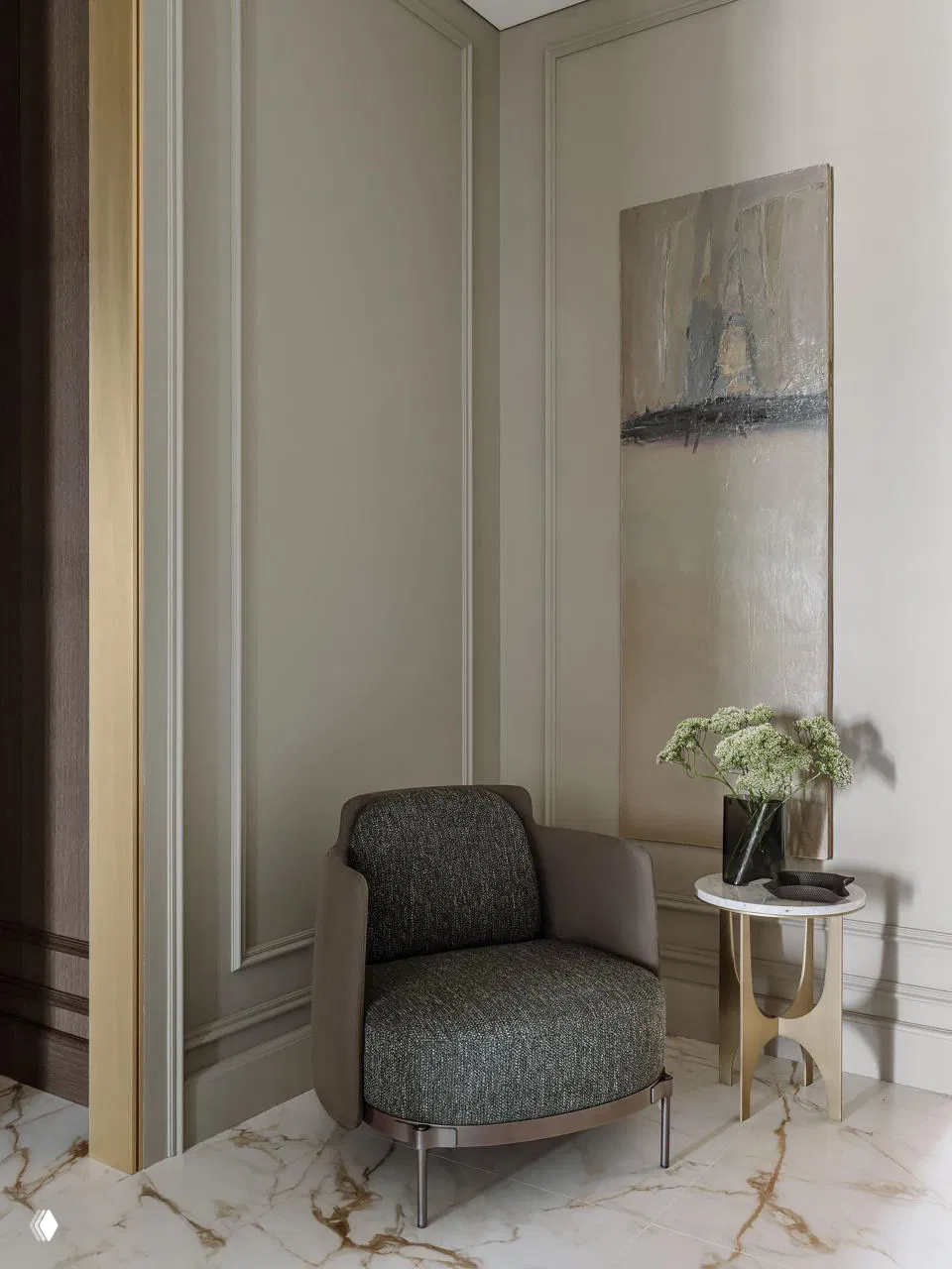 Небольшой уютный угол с дизайнерским креслом и мраморным столиком на фоне декоративных молдингов, благородного сочетания материалов и скрытой подсветки.