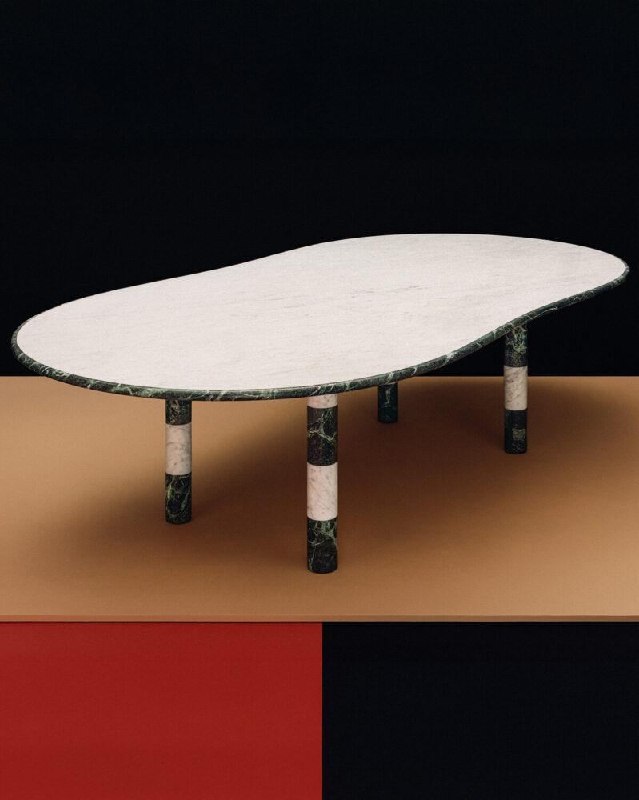 Крупный план мраморного стола с тонкой белой столешницей и цилиндрическими ножками из черного и белого мрамора, минималистичная композиция.