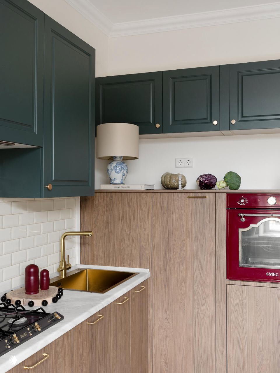 Кухонный фрагмент: тёмно-зелёные верхние шкафы, деревянные фасады, золочёная мойка и ягодный духовой шкаф SMEG — контрасты и детали в московской сталинке.