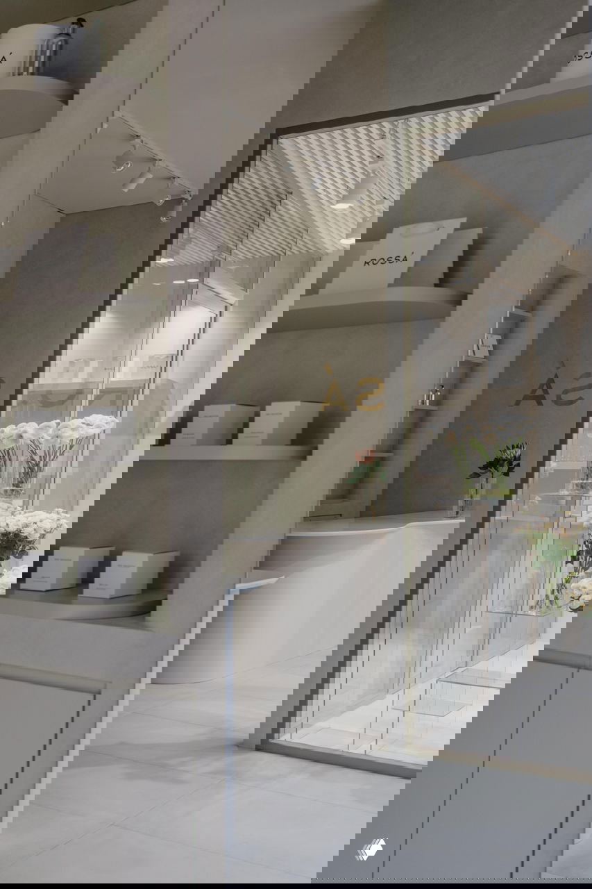 Вид из дверного проема на интерьер бутика: плавные формы, нейтральные поверхности и тщательно продуманная экспозиция цветов и упаковки бренда.