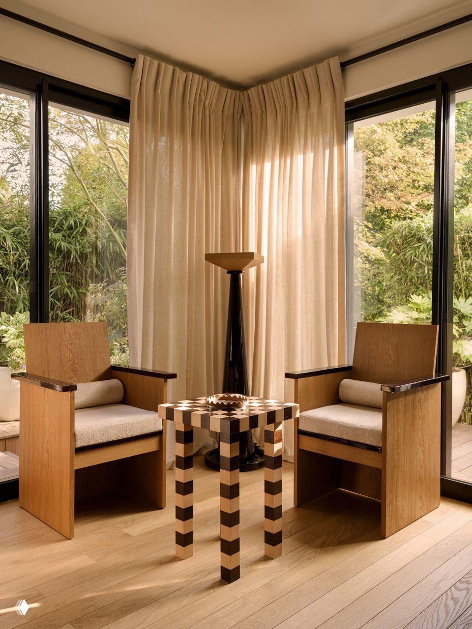 Уютный уголок с двумя деревянными креслами, стеклянными дверями на сад и шахматным низким столиком — акцент на натуральных материалах и симметрии.