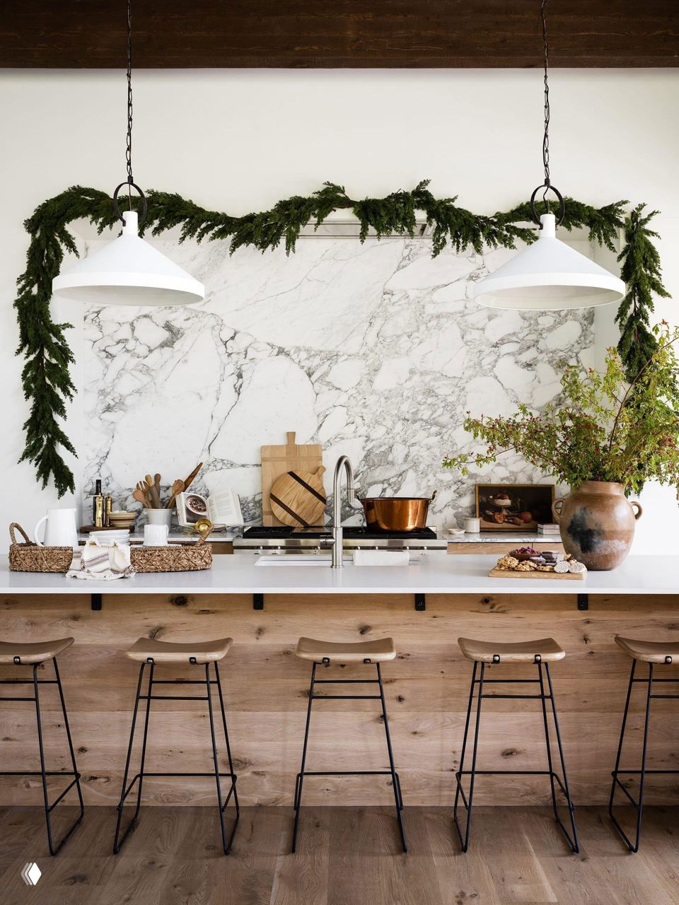Кухонная рабочая зона с мраморным фартуком, деревянной столешницей и подвешенной зеленью — простая праздничная композиция в естественных тонах.