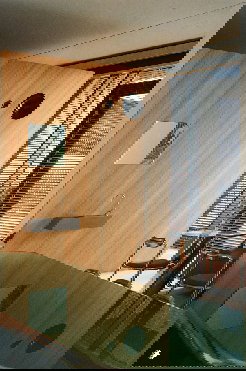 Стена из лиственницы с зеркалом и отражением полированной зеленой столешницы; сочетание древесной текстуры, стекла и хромированных деталей в зоне сервиса.