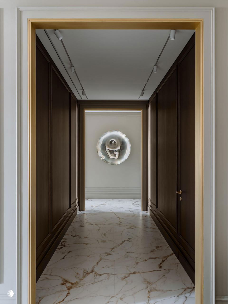 Широкий коридор с тёмными деревянными панелями, мраморным полом и световой арт‑инсталляцией в торце, подчёркивающей глубину и монохромные тона интерьера.