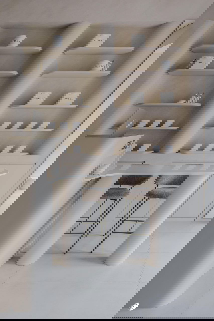 Ресепшн и барная столешница в светлых тонах с округлыми опорами, на фоне аккуратно организованных полок с фирменной упаковкой Rossa и декоративными элементами.