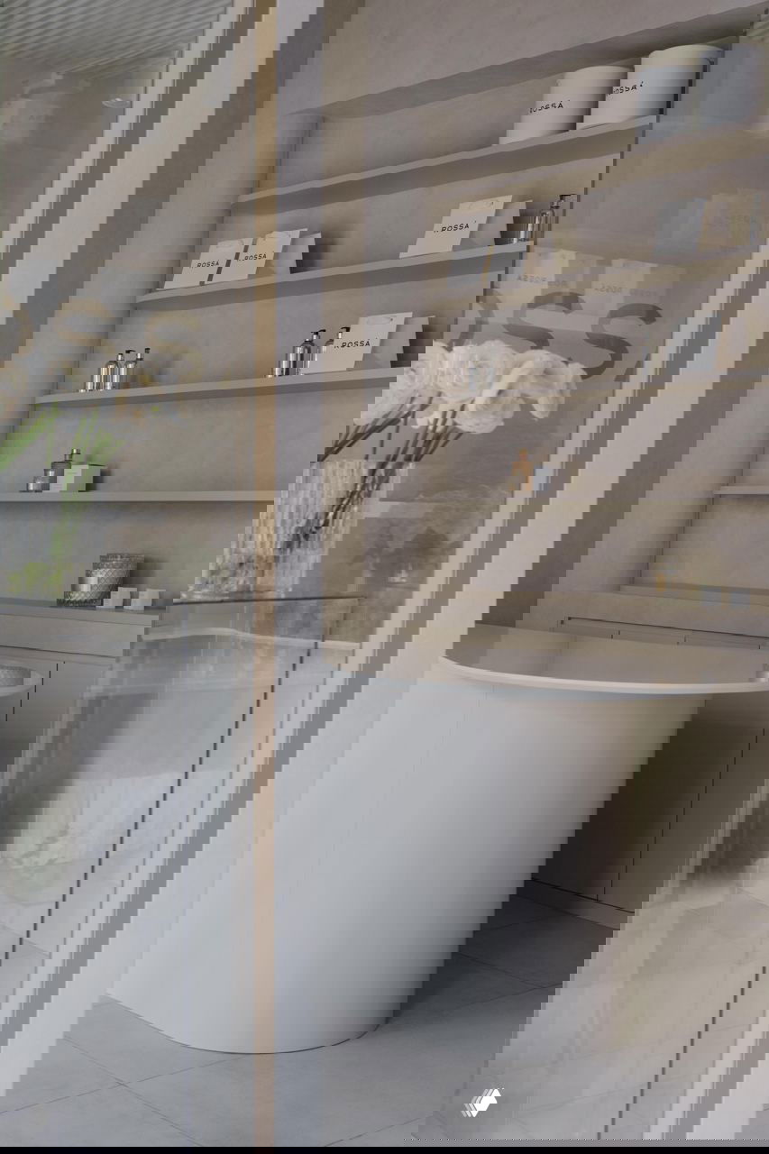 Уголок бутика с закругленной столешницей и открытыми стеллажами, где минимализм сочетается с практичной организацией товара и светлой отделкой.