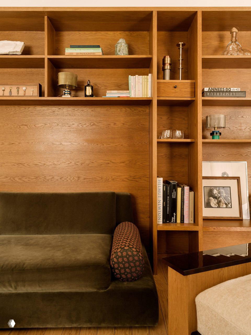 Встроенные деревянные полки над низким диваном, сочетание открытых полок и аксессуаров — тёплая древесная отделка в минималистичной гостиной.