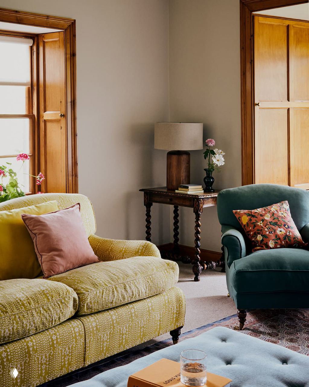 Гостиная с мягкими диванами зелёного и жёлтого оттенка, низким пуфом и деревянной декоративной тумбой — сочетание антикварных форм и современных тканей.