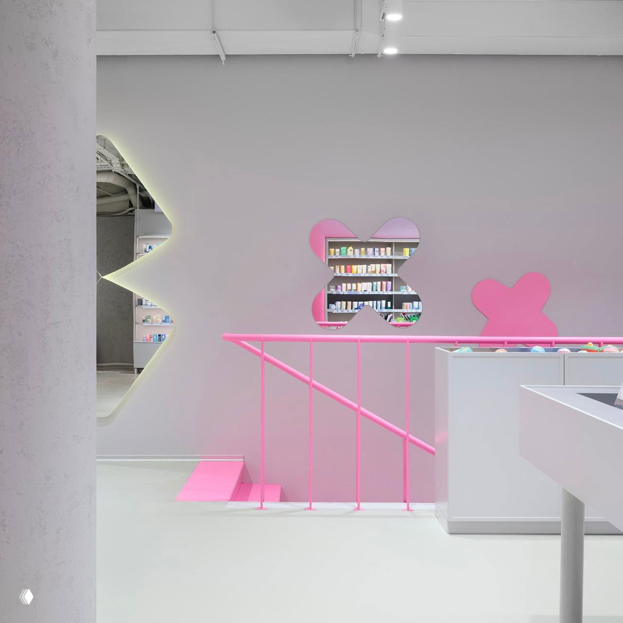 Вид с другого ракурса: круглые столы с помадами и баночками на переднем плане, аккуратные стеллажи, яркая розовая палитра и торговая планировка магазина Hollyshop.