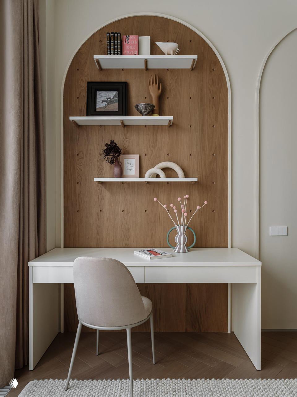 Рабочая зона у окна: белый стол, мягкий стул и декоративные полки на фоне арочной деревянной ниши — компактный функциональный уголок в квартире.