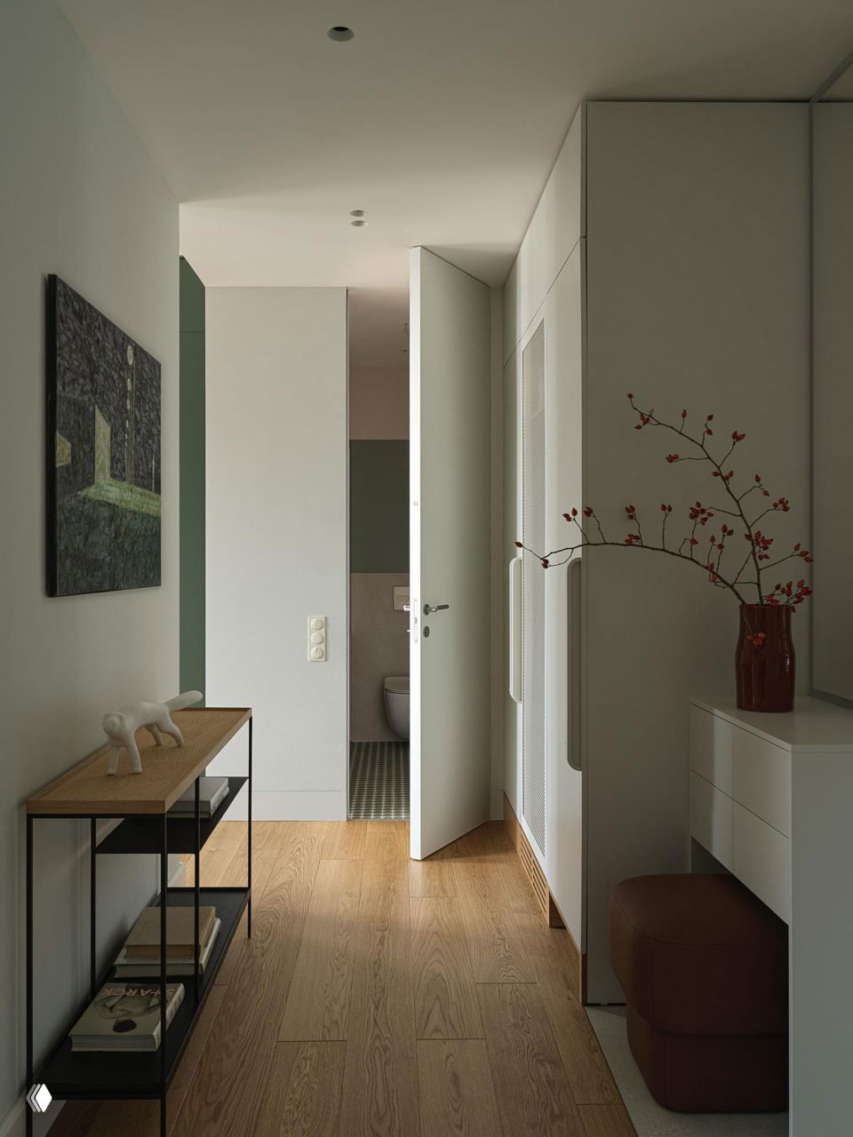 Светлый коридор с открытой дверью в санузел, лаконичная консоль на металлическом каркасе, деревянный пол и вазочка с веткой на столике