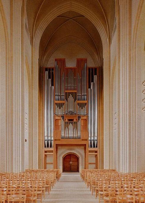 Фрагмент интерьера с органом: деревянные трубы органа и центральная ось нефа, усиливающие торжественную, но сдержанную выразительность пространства.