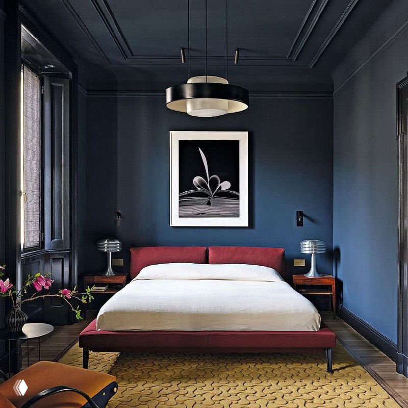 Деталь проёма и дверной ручки в миланской квартире: перспектива на комнату с мягким диваном, яркие цветы в вазе и декоративный паркет.