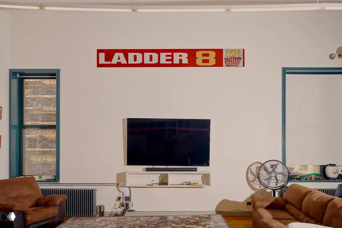 Комната отдыха внутри пожарной части с диванами, телевизором и баннером LADDER 8 на стене — бытовое пространство пожарных