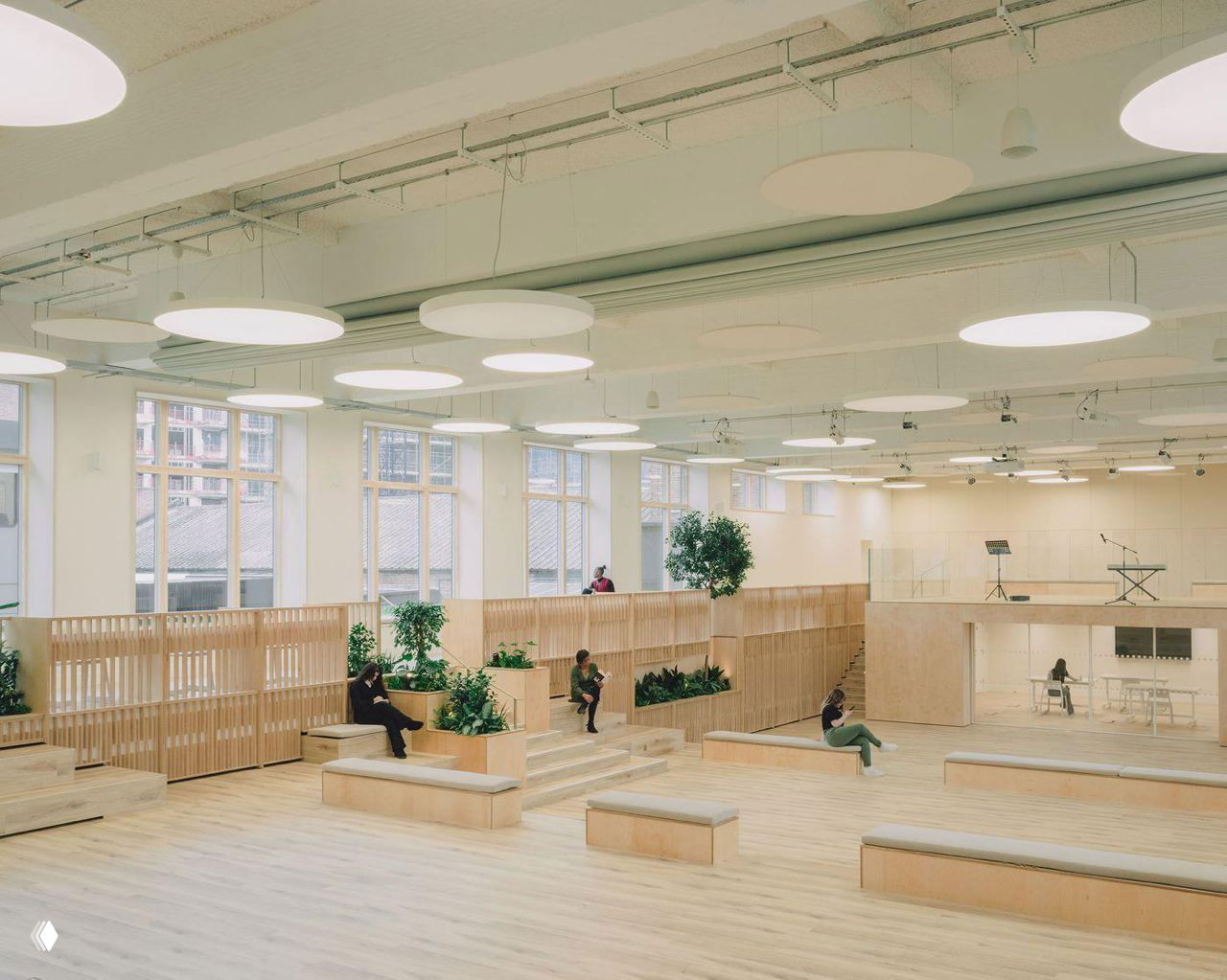 Коридор и балкон учебного центра с поручнями, посадочными местами и крупными окнами, акцент на белую палитру и дерево для усиления естественного света.