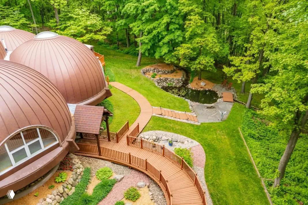 Крупный план террасы и дорожки у дома, заметен декоративный пруд и каменная кладка в оформлении участка рядом с куполами.