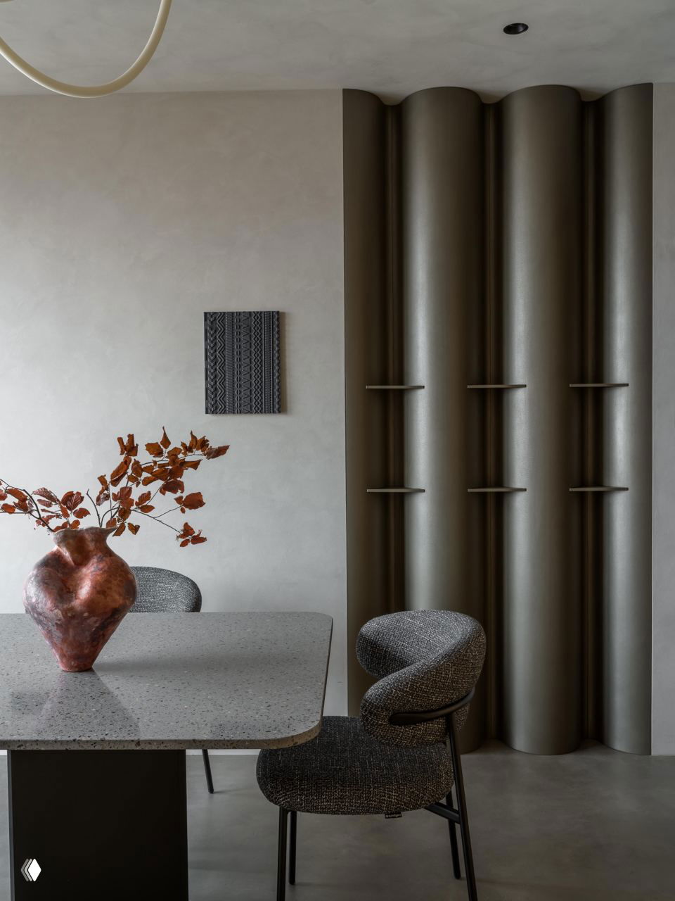 Обеденная зона: стол с каменной столешницей, изогнутые стулья и декоративная панель с цилиндрическими вертикальными колоннами, тёплая гамма.
