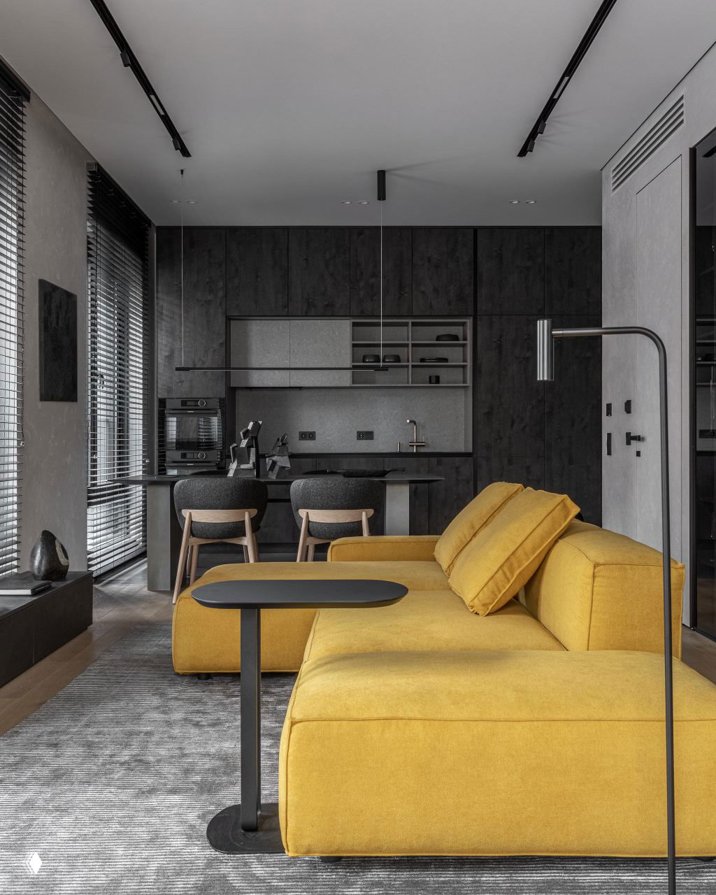 Жёлтый угловой диван на фоне тёмной встроенной кухни и барной стойки — контрастная палитра и лаконичная мебель в проекте 56 м².