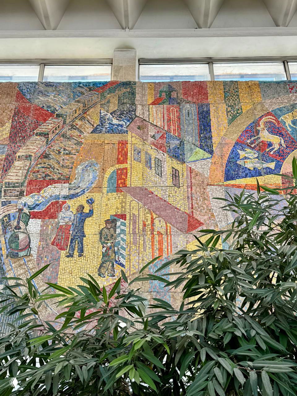 Деталь правой части мозаики с изображениями поезда, взлетающего самолёта, студентов и рабочих хлопчатобумажного комбината «Пролетарка» в художественной манере.