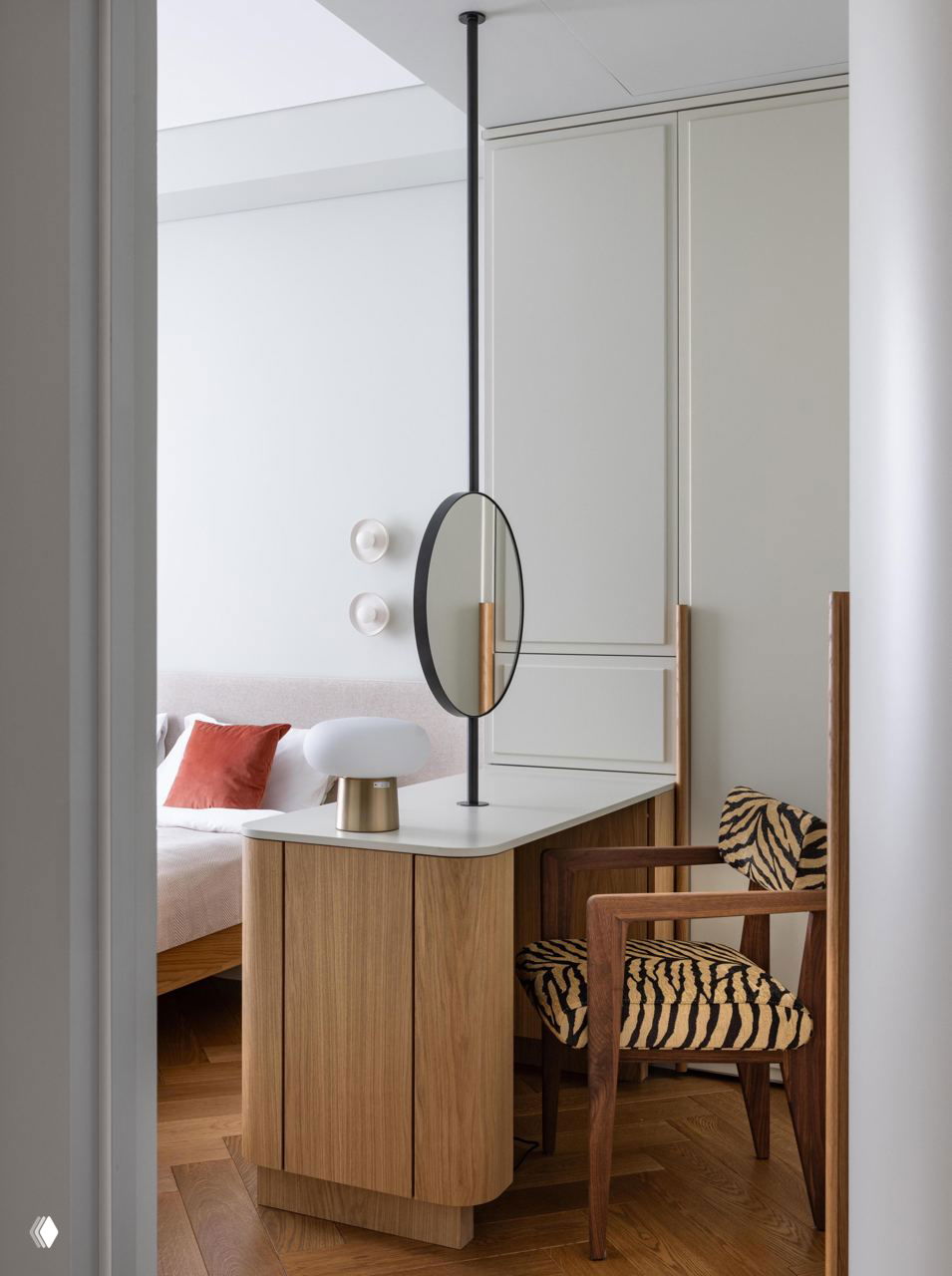 Узкая зона туалетного столика с круглым вертикальным зеркалом, деревянной мебелью и креслом в тигровом принте рядом с кроватью
