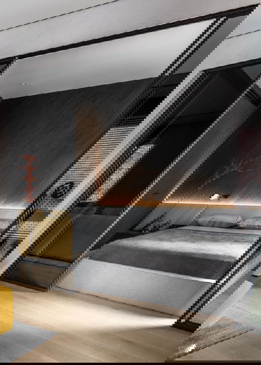 Спальня за раздвижной стеклянной перегородкой: низкая кровать, тёмные стеновые панели и мягкая подсветка вдоль изголовья.