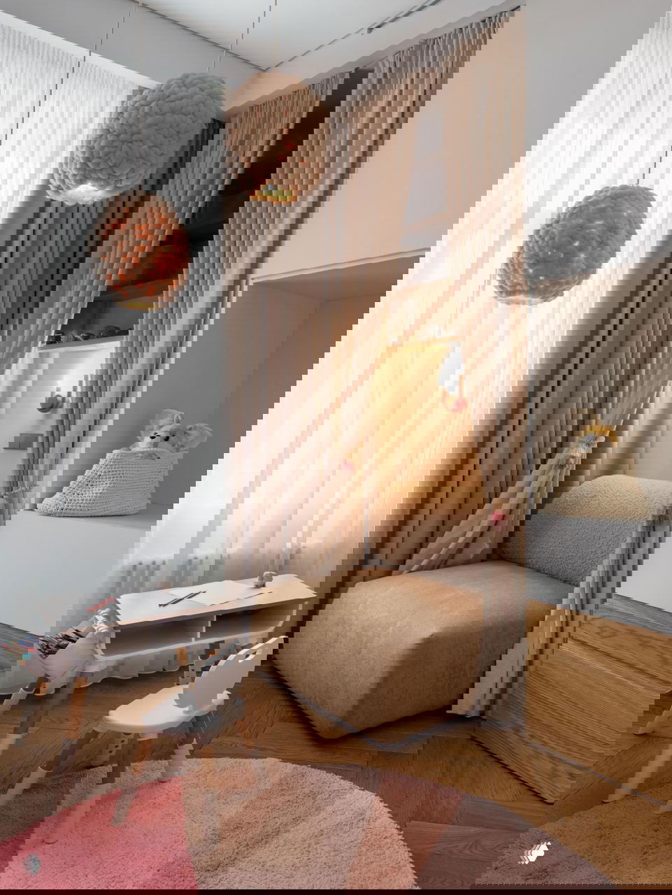 Детский уголок у окна: мягкое кресло за шторами, маленький столик для творчества и воздушные занавеси, создающие уютную нишу