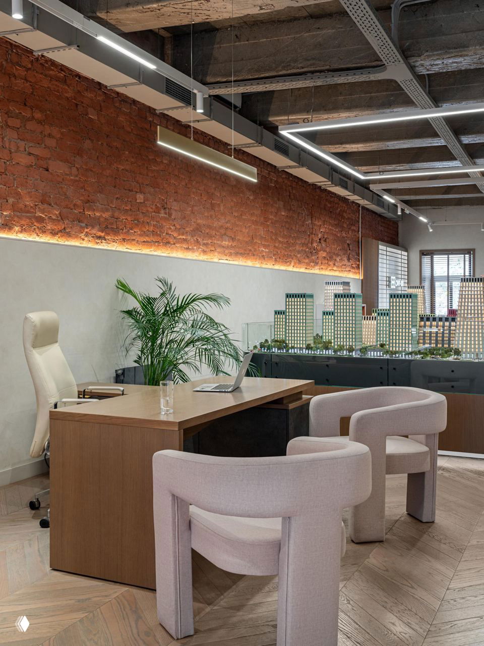 Стол для переговоров и макет застраиваемого квартала на фоне кирпичной стены с подсветкой, модель квартала как центр планировки интерьера.