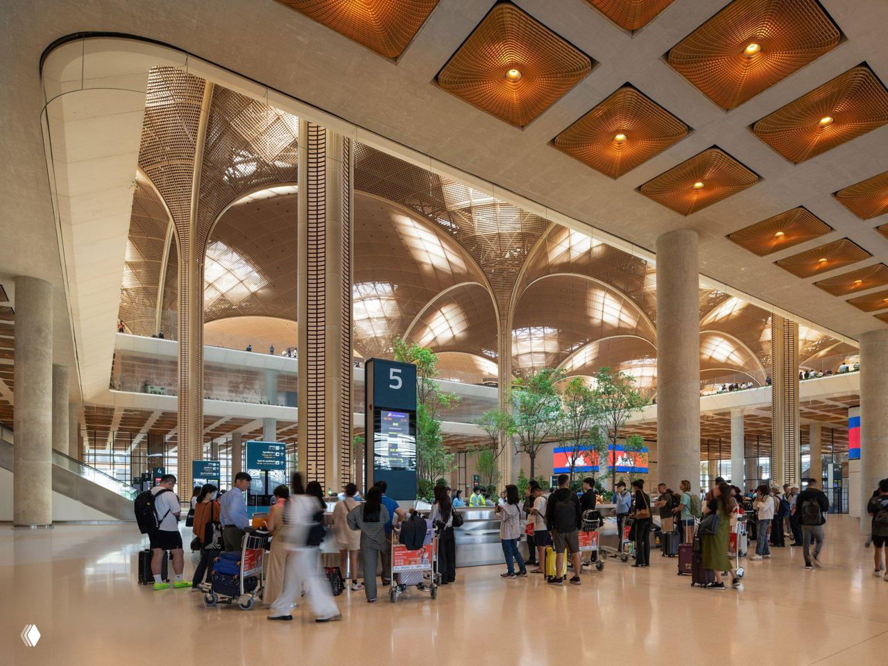 Зона регистрации и прохода: стойки, очереди пассажиров, эскалаторы и крупные колонны на фоне знаменитых арочных сводов крыши аэропорта.