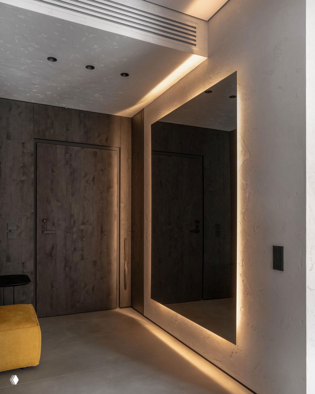 Прихожая с большим подсвечиваемым зеркалом, тёмными дверями и мягким полом — лаконичная входная зона в минималистичном стиле.