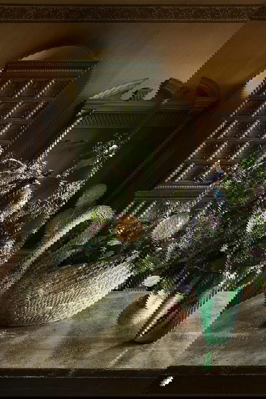 Декоративная композиция на рабочем столе поместья: керамическая фигура-лебедь, зелёная кафельная печь, вазы и ветви с рождественскими украшениями на Рождество в поместье на Фюне.