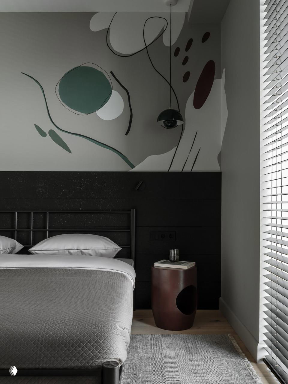 Спальня с тёмным изголовьем и крупным абстрактным настенным рисунком; сдержанная гамма текстиля и лаконичная прикроватная тумба.