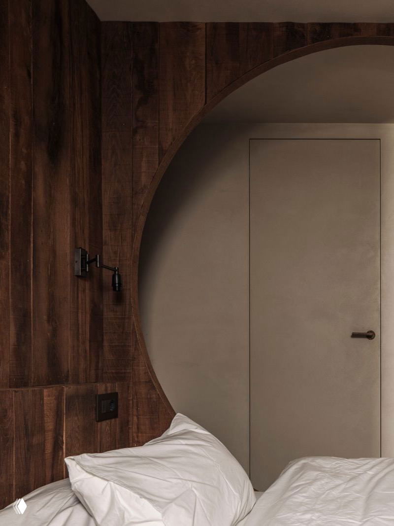 Просторная светлая гостиная: встроенные лавки, грубая деревянная мебель и камин на фоне минималистичных светлых стен и гладкого бетонного пола.