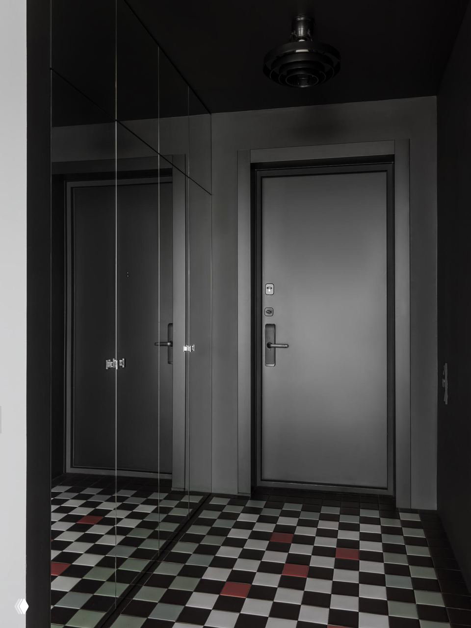 Прихожая с зеркальными фасадами шкафов и чёрной входной дверью; на полу графичная шахматная плитка с контрастными акцентами в отделке.